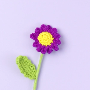Detailed view of handmade crochet daisy flower with purple petals and yellow center