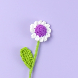 Close-up of handmade crochet daisy flower with white petals and a lavender center