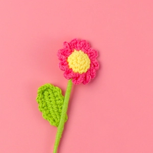 Detailed texture of handmade crochet pink daisy flowers with bright yellow centers