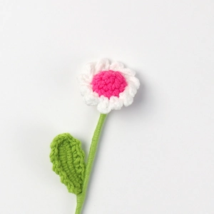 Close-up of handmade crochet daisy with white petals and vibrant rose pink stamen