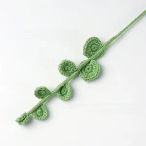 Close-up of handmade crochet eucalyptus branch with seven leaves and wool texture
