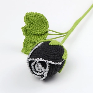 Detailed view of handmade crochet black rose with silver edges and green leaves