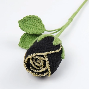 Detail of handcrafted black and gold crochet rose with green leaves and stem on white back