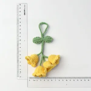 Detailed view of handmade yellow crochet lily of the valley charm with rulers for scale