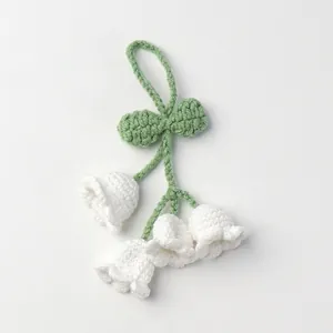 Detailed macro view of handmade crochet lily of the valley flowers with green leaves