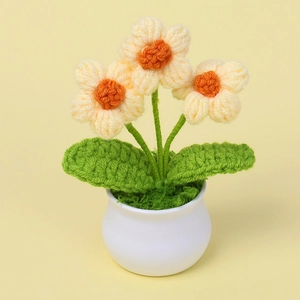 Detalle macro de miniflores de ganchillo hechas a mano con pétalos crema en maceta blanca