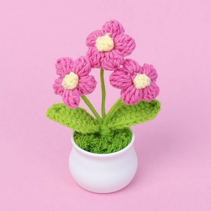 Primer plano de maceta de flores tejidas a mano rosa con base cerámica para escritorio