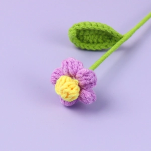 Dettaglio ravvicinato di fiore a sbuffo viola lavorato all'uncinetto con foglie e stelo