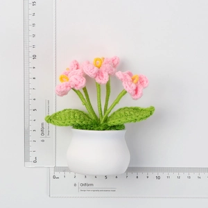 Detailed view of handmade crochet pink flower pot with measuring rulers for size