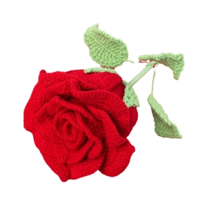 Handmade crochet red yarn rose with green leaves on white background for home decor