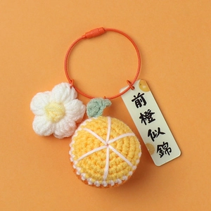 Macro detail of hand-crocheted orange persimmon keychain with festive tag on orange background
