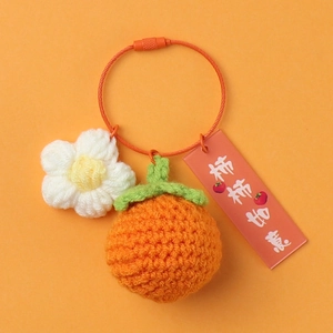 Macro detail of handmade crochet persimmon keychain with orange yarn and gift tag