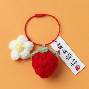 Macro shot of handmade crochet strawberry keychain with flower and red wire ring