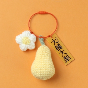 Handmade crochet pear keychain with white flower charm on vibrant orange background