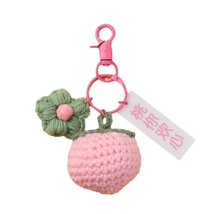 Pink crochet peach keychain with green leaf and flower on white background