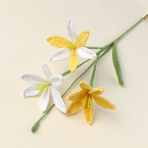 Detailed view of handmade crochet lily flowers with yellow and white petals on green stems