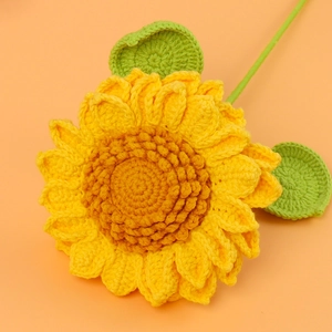 Handmade crochet sunflower with yellow petals and brown center on orange background