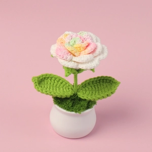 Detail view of handmade crochet rainbow rose in white ceramic pot for desk decoration