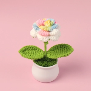 Handmade knitted crochet rose flower in white ceramic pot on pink background