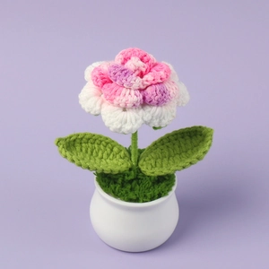 Detailed macro of handmade crochet flower in white pot with soft pink and purple petals