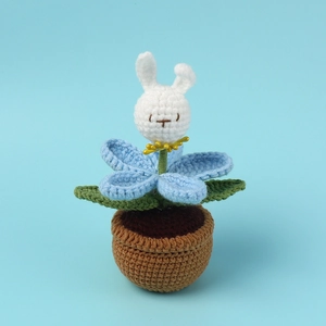 Detailed view of handmade crochet bunny flower pot with blue petals and green leaves