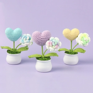 Detailed close-up of handmade crochet heart and flower mini potted plants on lavender background