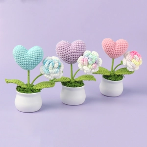 Detailed close-up of three handmade crochet mini potted plants with hearts and flowers