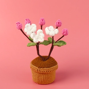 Plante en pot de fleurs de cerisier crochetée à la main avec fleurs blanches sur fond rose