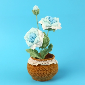 Macro shot of handmade crochet flowers in blue and white with delicate lace pot