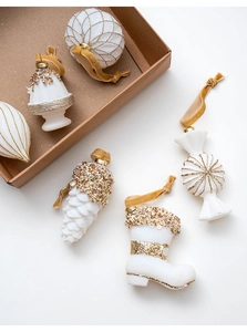 Detail of white and gold Christmas ornaments with glitter patterns and velvet strings