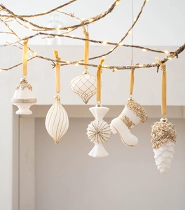 Detailed close-up of six white and gold Christmas ornaments with velvet ribbons on a tree