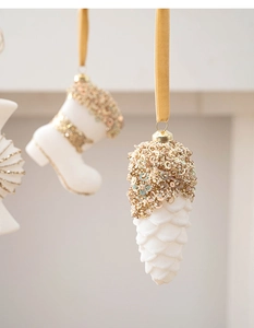Detail of pinecone and boot Christmas ornaments with golden sequins and satin hanging ropes