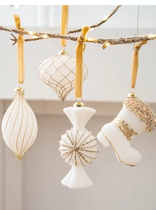 Close-up of pearl white and gold Christmas ornaments with velvet hanging ropes