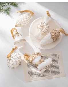 Close-up of white flocked Christmas ornaments with gold glitter details in a festive setting