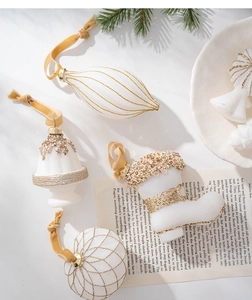 Detailed cream Christmas ornaments with gold glitter and sequins on a festive pine background