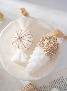 Detail of white flocked candy and pine cone ornaments with gold glitter and sequins