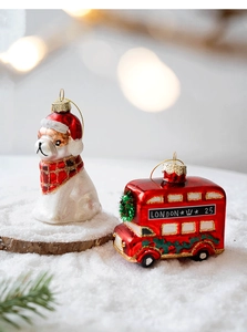 Close-up of glass Christmas ornaments featuring a white dog and London bus on snow