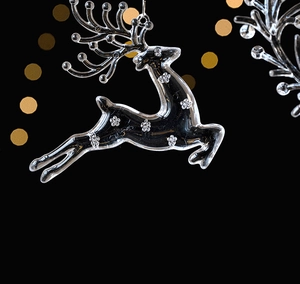Detail of transparent deer Christmas ornament with white floral patterns on black background