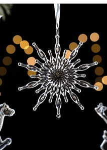 Close-up of a clear crystal snowflake ornament with a white ribbon for Christmas trees