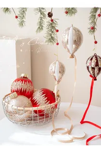 Gros plan d'ornements de Noël rouges et champagne avec paillettes sur branches de sapin