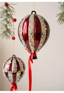Détail d'un ornement de Noël en forme de montgolfière rouge avec paillettes et ruban