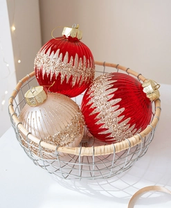 Vue détaillée de boules de Noël champagne et rouges avec des motifs de paillettes dorées