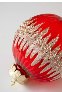 Macro d'une boule de Noël en verre rouge avec paillettes dorées et détails perlés