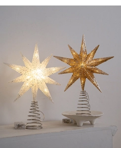 Detail of champagne and white LED lit star tree topper with glitter and spring base
