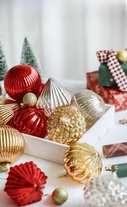 Detail view of assorted Christmas glass ornaments in red and gold inside a wooden tray