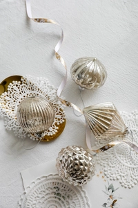 Detailed view of champagne gold mercury glass Christmas ornaments in four unique shapes