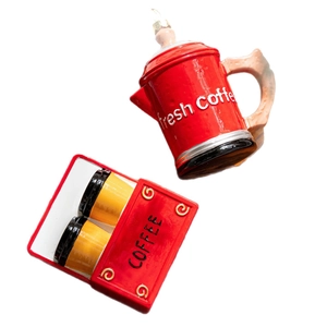 Set di decorazioni natalizie con caffettiera rossa e due tazze gialle su sfondo bianco