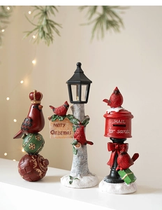 Detailed view of resin Christmas ornaments featuring red birds on mailboxes and lamps