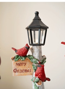 Close-up of a Christmas street lamp with resin cardinals and Merry Christmas sign