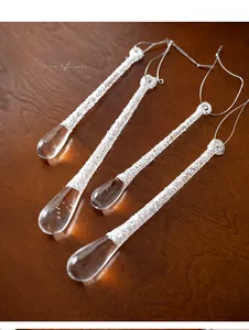 Macro shot of four transparent acrylic glitter icicle ornaments on dark wood background